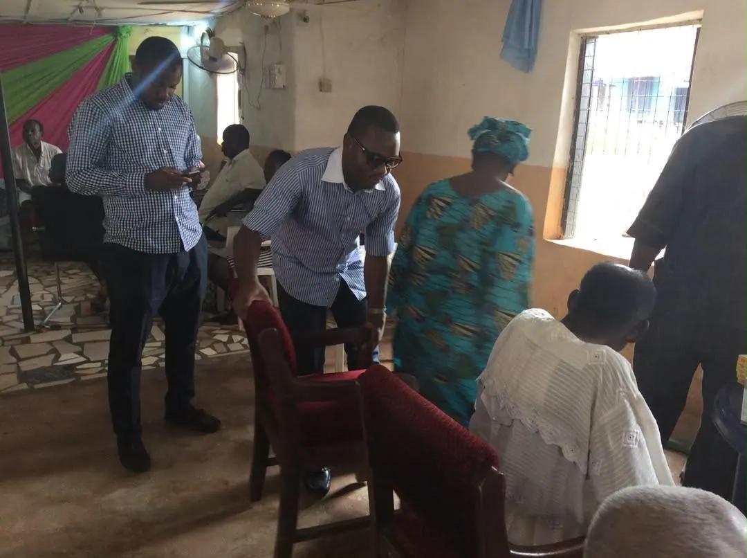 Volunteers assist an elderly woman inside a hall during a medical outreach.