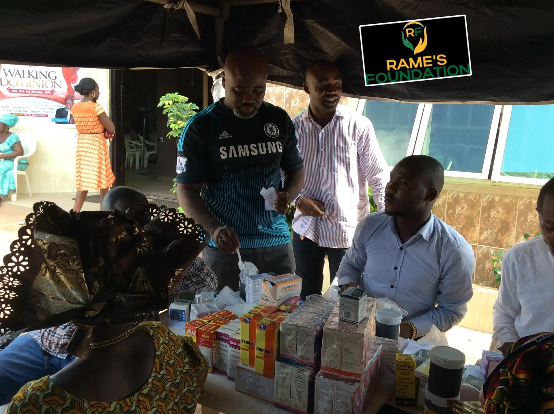 Volunteers hand out medicines to women seated at an outreach table.
