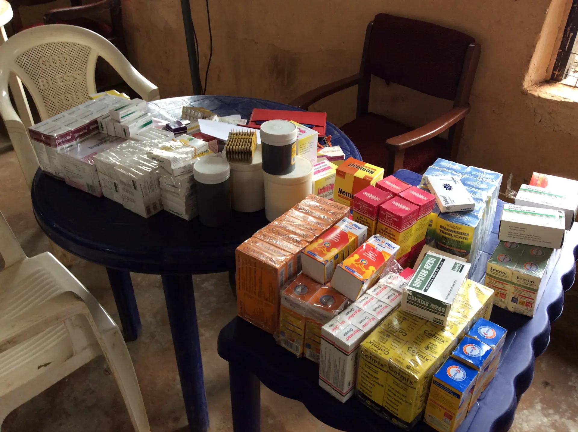 Boxes of medicines laid out on a table with white chairs ready for consultations.