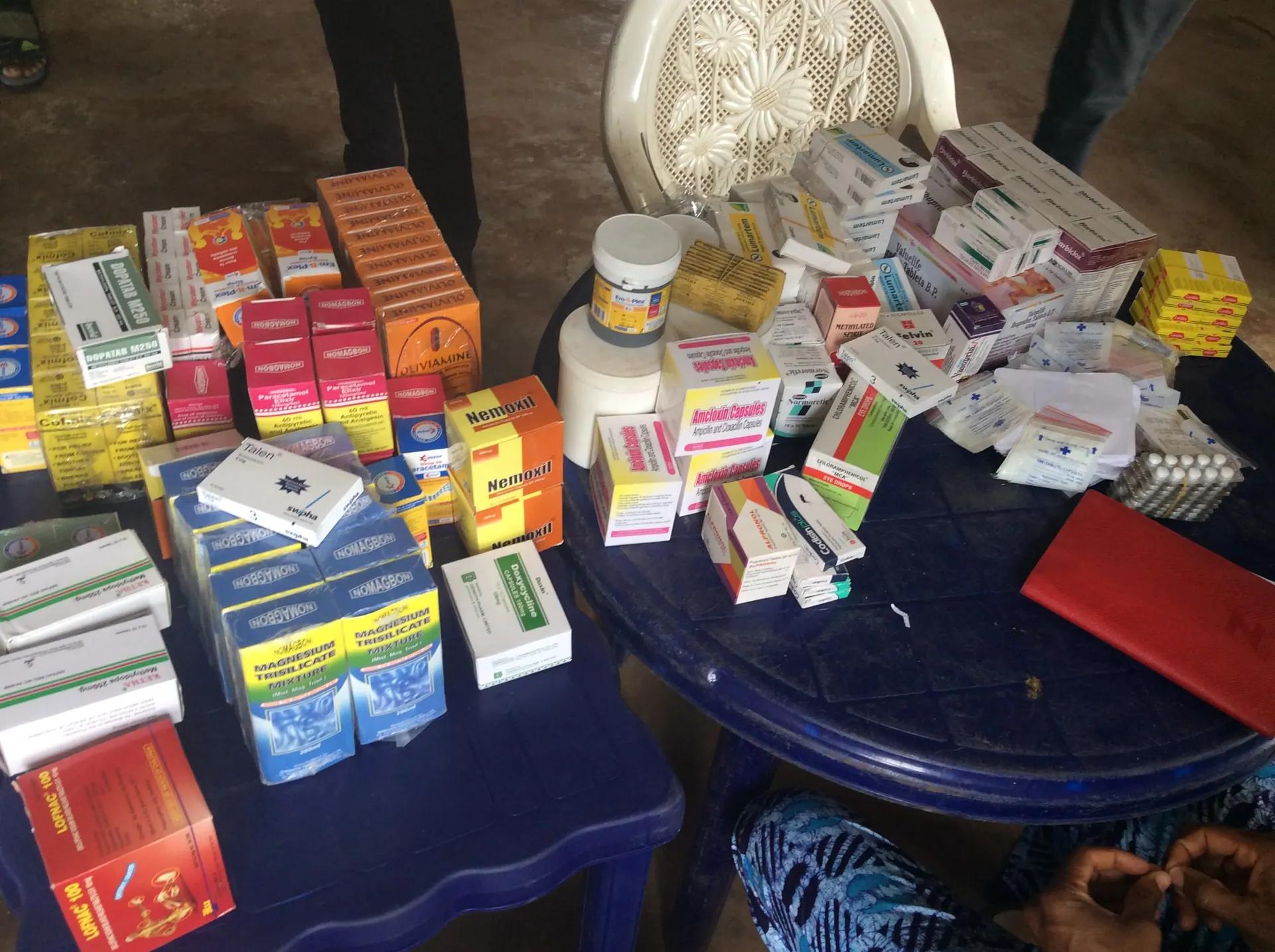 A table stacked with boxes of medicines and supplements prepared for free distribution at a medical outreach.