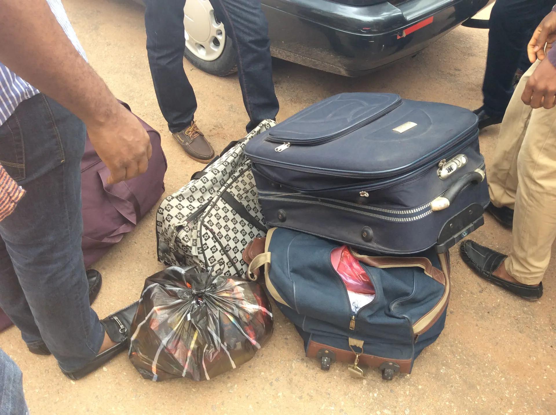 Bags and suitcases of relief supplies unloaded from a vehicle before a community distribution.