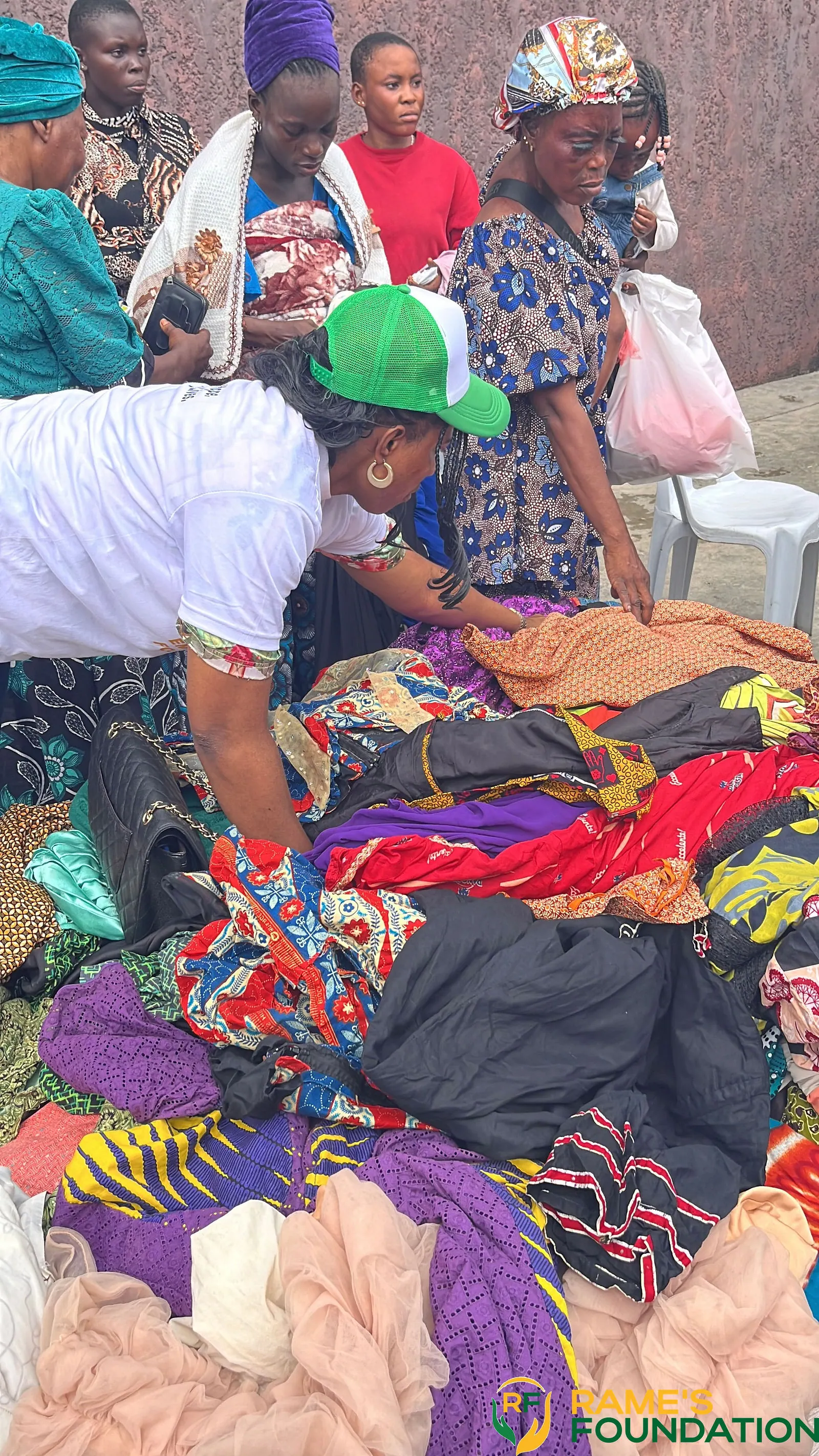A volunteer in a green cap sorts through a large pile of donated clothing.