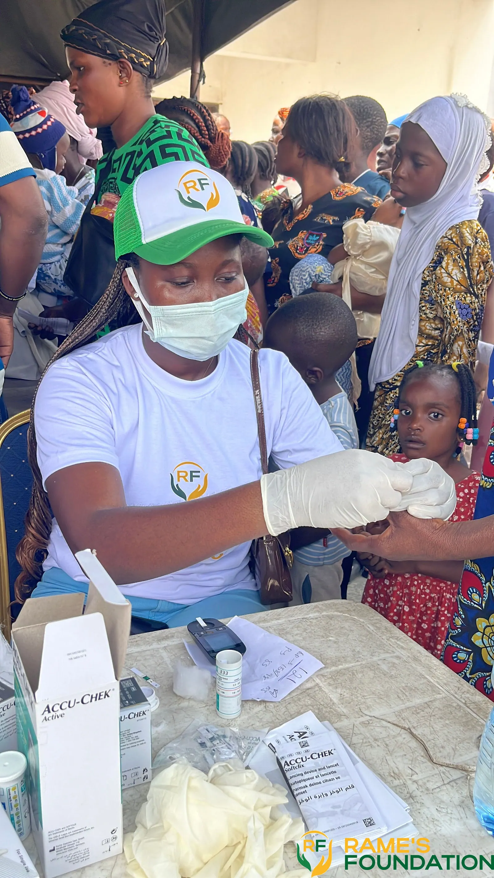 A gloved, masked volunteer performs a finger-prick blood test for a resident at a community outreach.