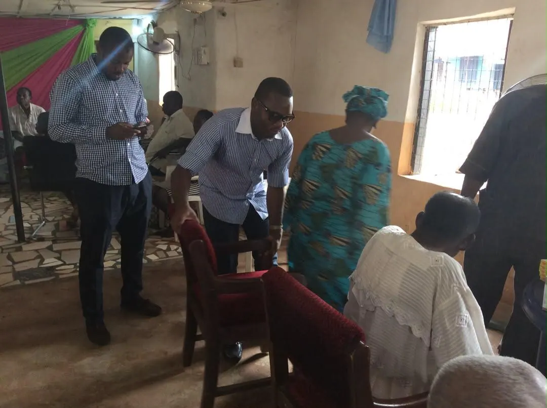 Volunteers assist an elderly woman inside a hall during a medical outreach.