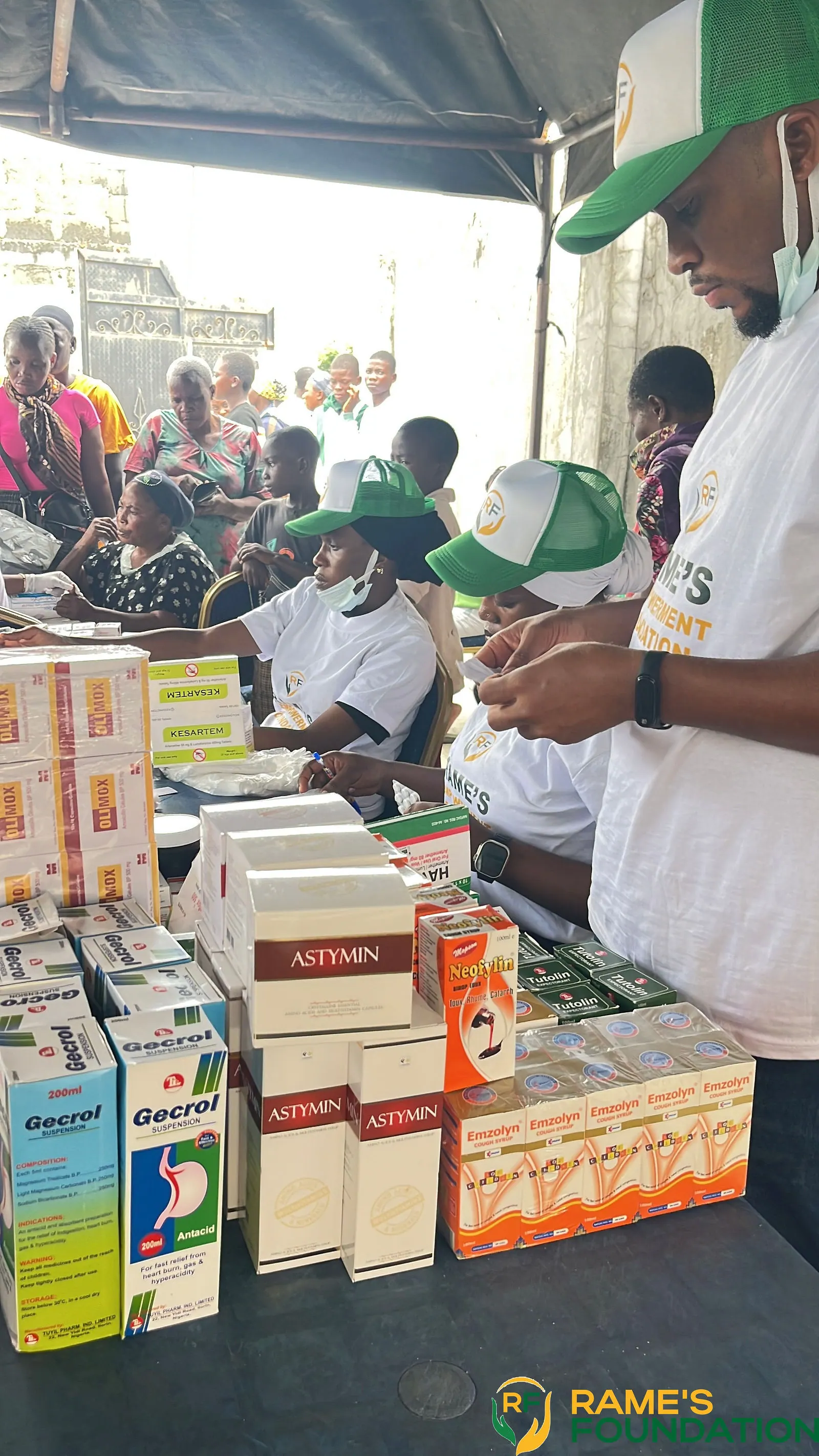 Boxes of medicines and supplements stacked on a table for free distribution.