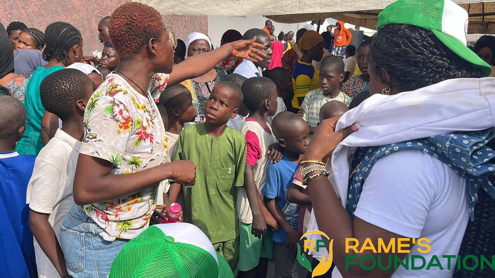 Children and parents press forward as RAMES volunteers distribute items at a community outreach.