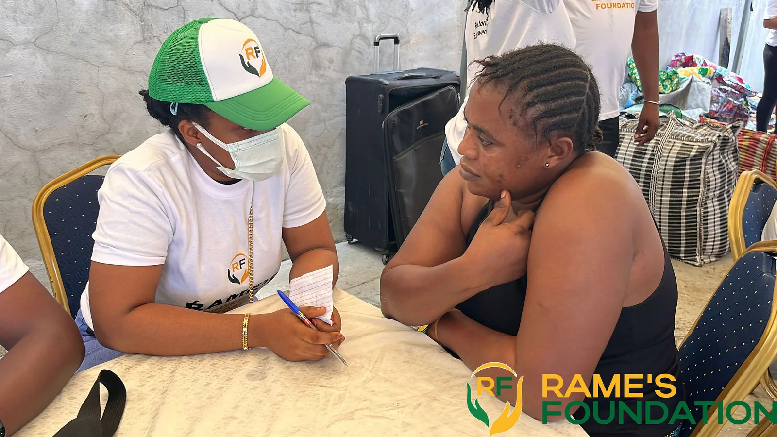 A masked volunteer writes down a resident's details at the registration desk of a medical outreach.