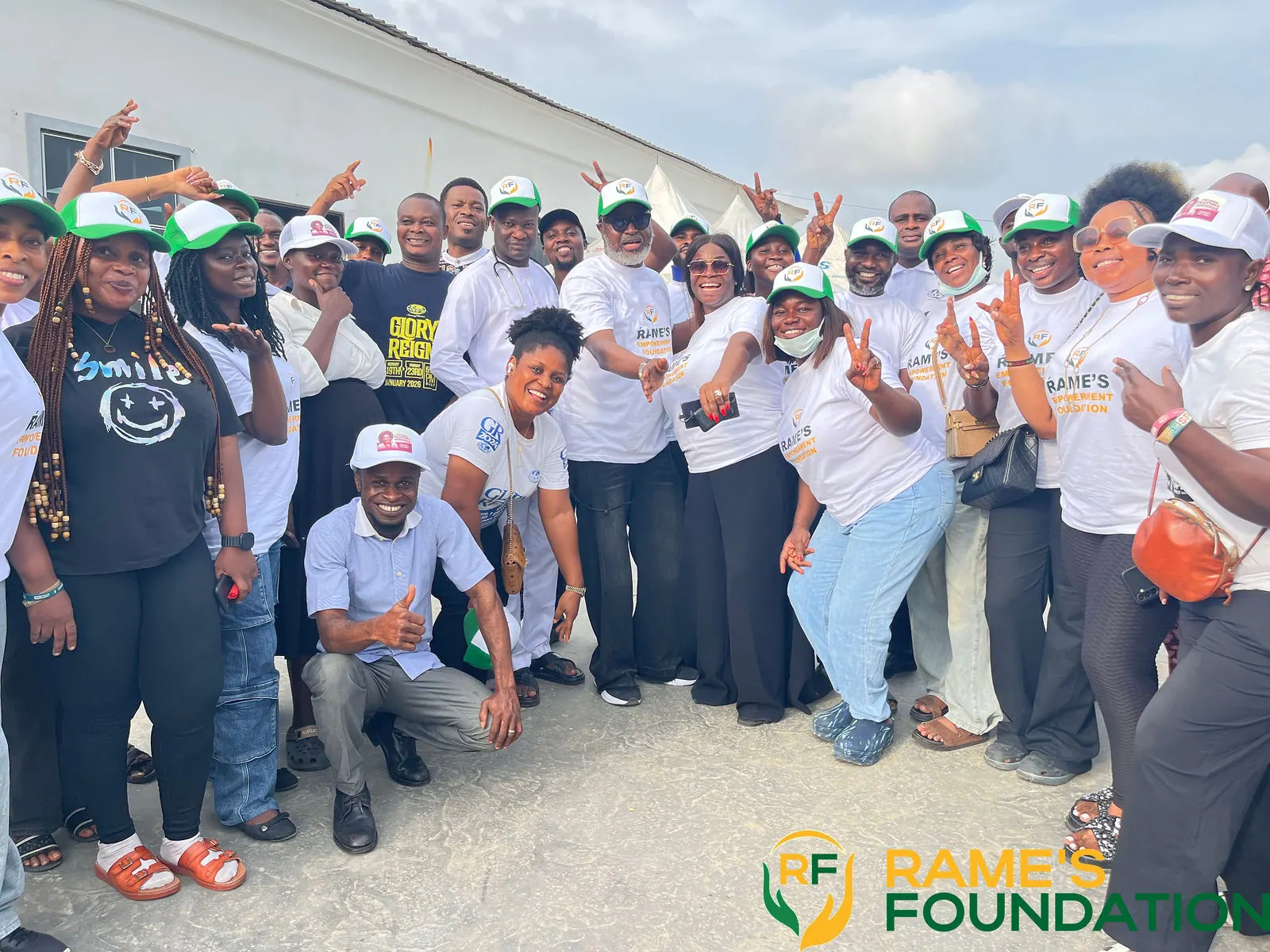 A crowd of RAMES volunteers pose joyfully with raised hands after the outreach.