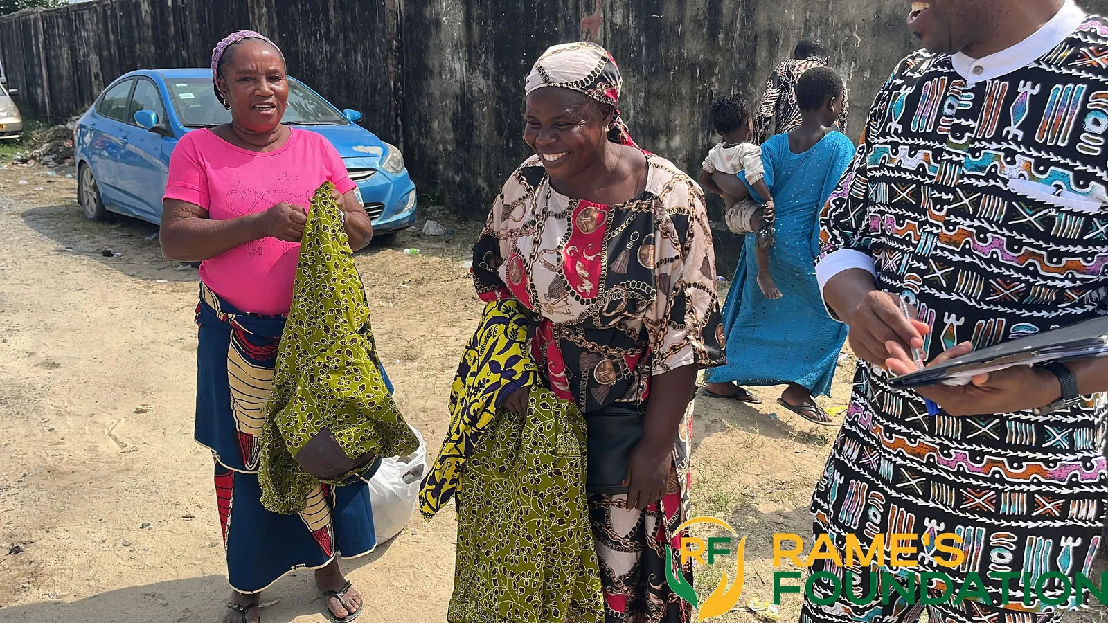Two smiling women hold up the clothing they received at a community outreach.
